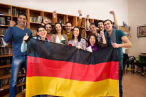 Multinationale Menschen stehen froh hinter Deutschlandfahne