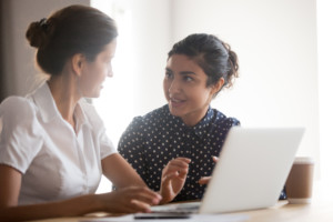 Mentorin hilft einer jungen Frau vor laptop