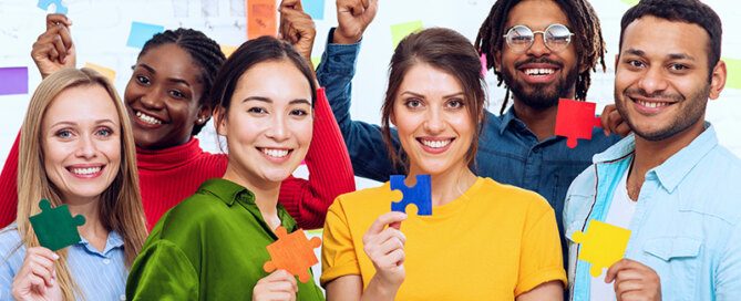Gruppe internationaler Menschen halten bunte Puzzleteile
